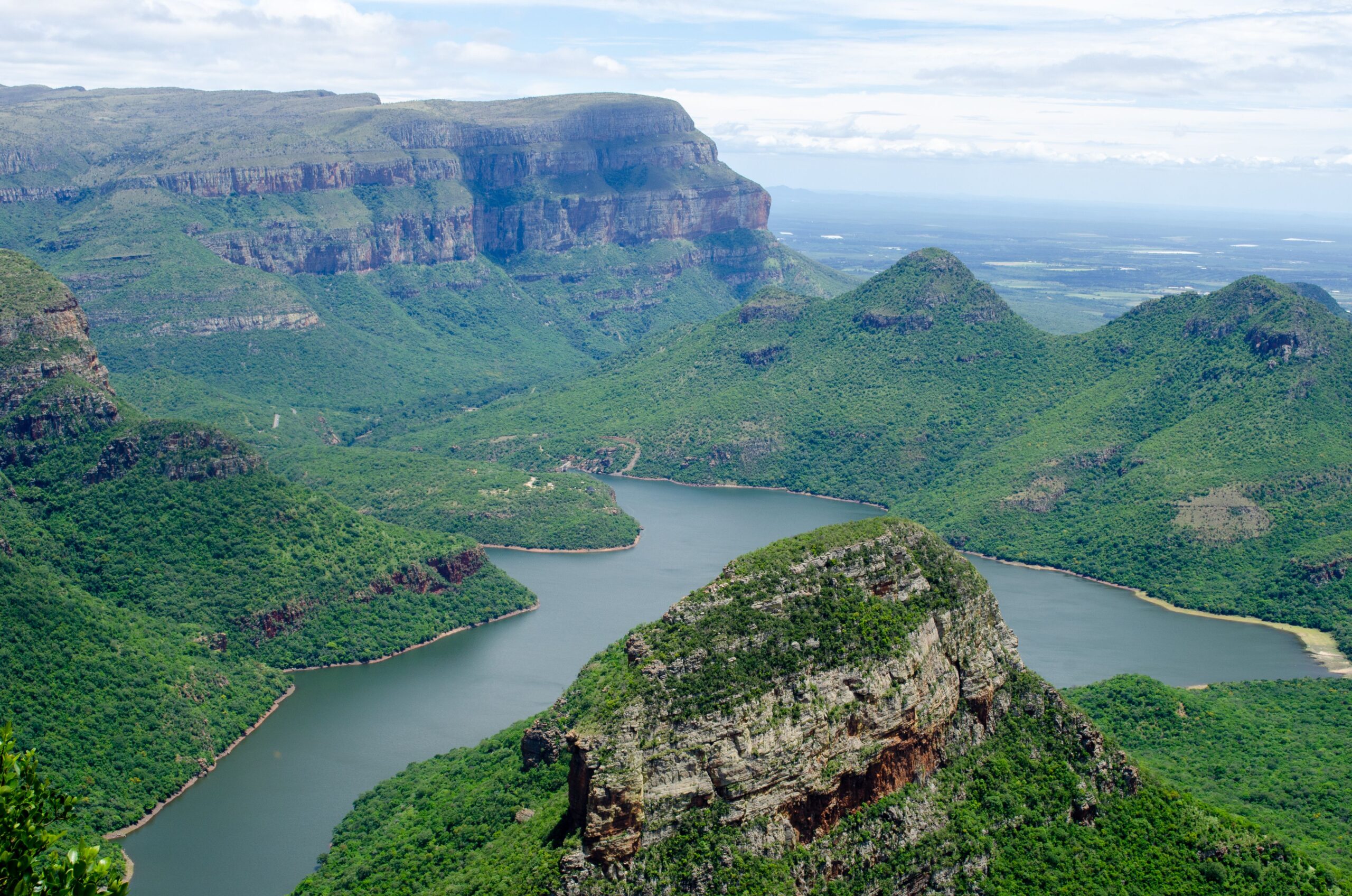 Enjoy the breathtaking aerial view of a lush green canyon landscape with a winding river.