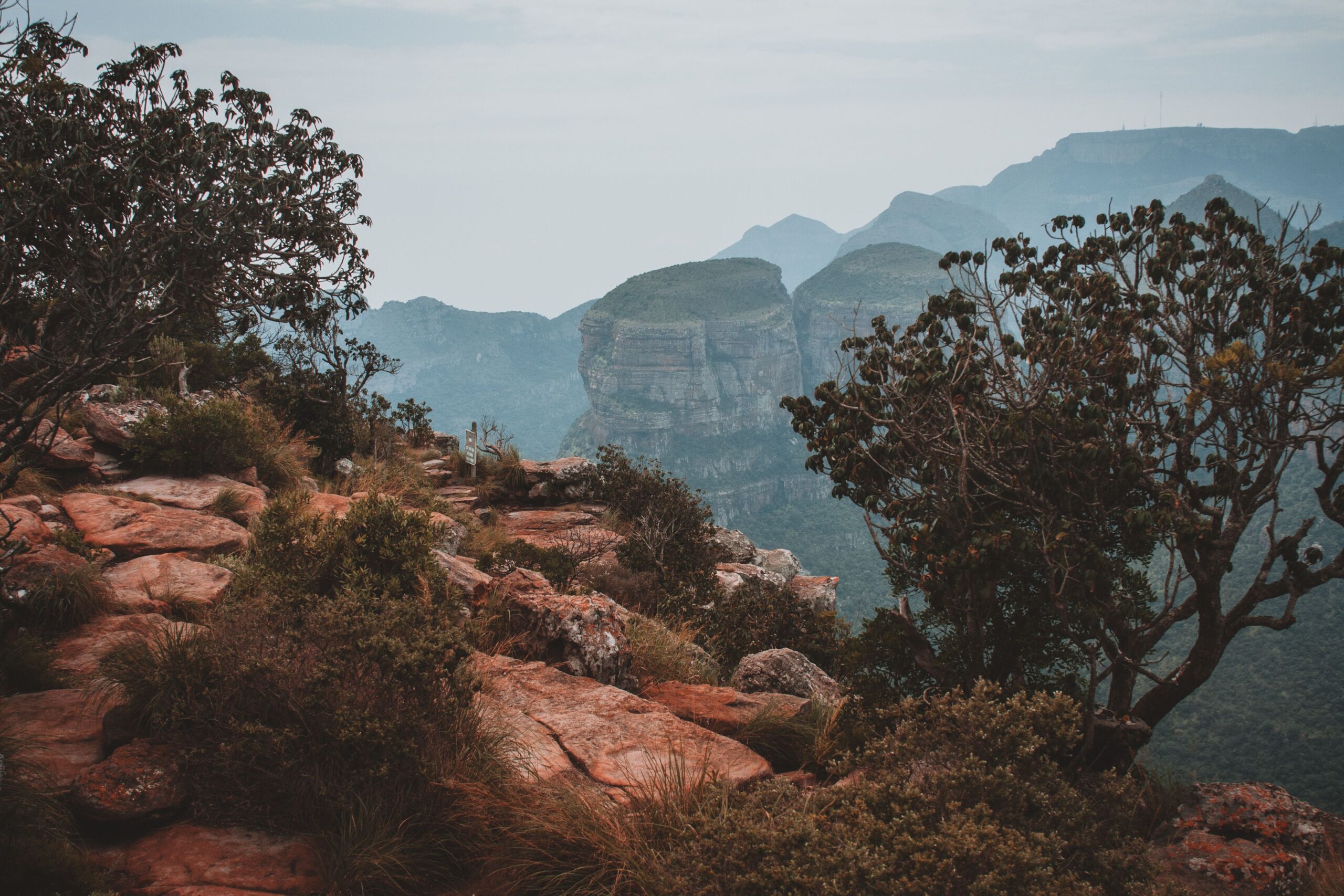 Breathtaking mountain landscape featuring a rocky cliff and lush greenery at dawn.